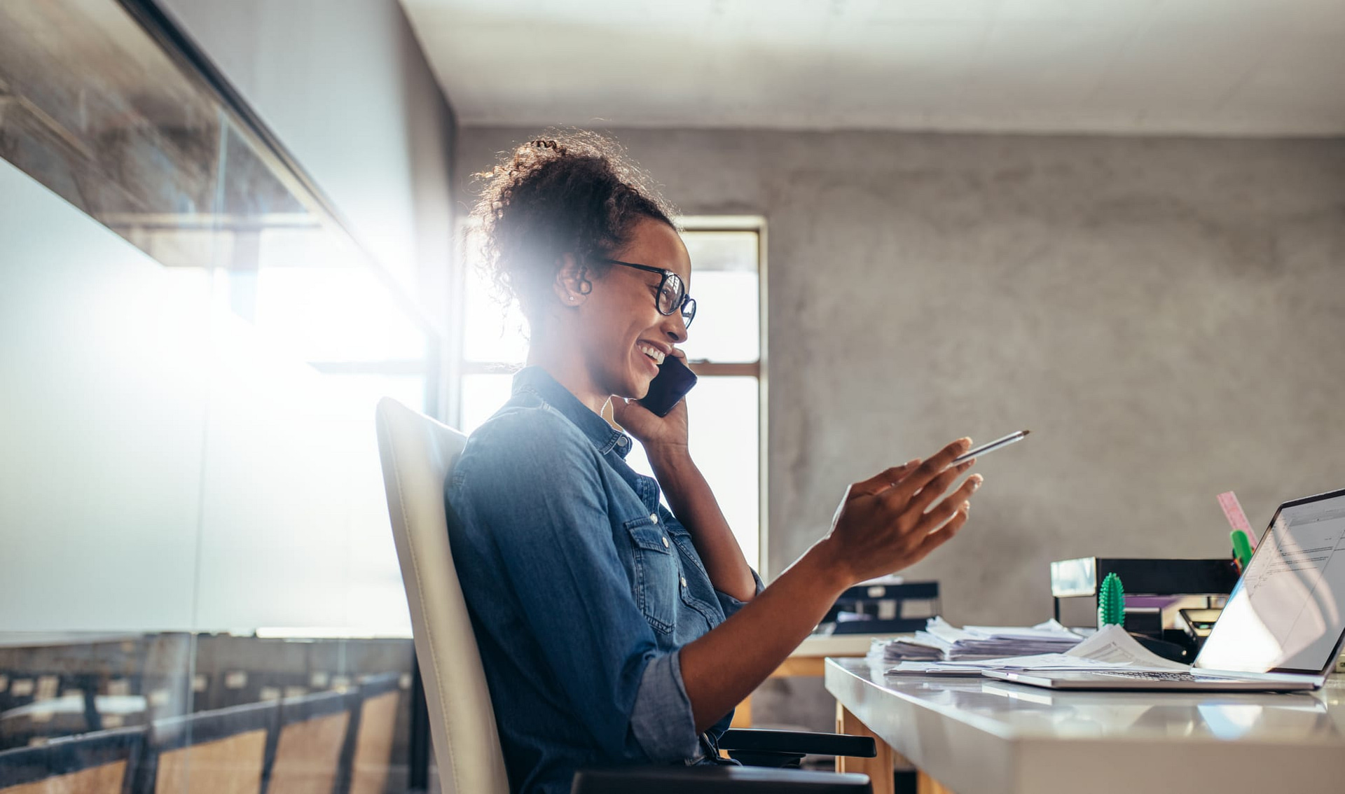 business woman in a blue shirt talking on the phone in an office