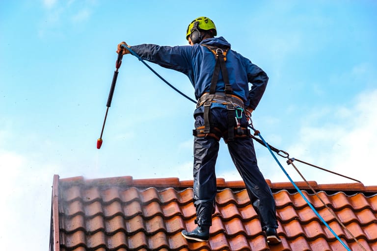 man pressure washing the tile roof