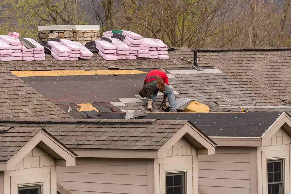 Roofing contractor installing shingles on roof