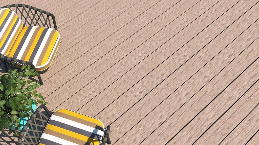 Patio furniture with striped yellow, black, and white cushions next to a leafy plant on a wooden deck.