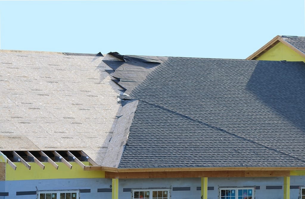 Partially finished roof with dark shingles covering the right side