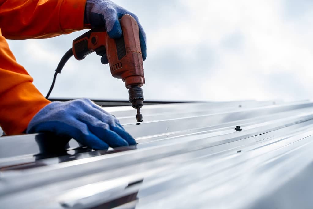 roofer drilling metal roofing on commercial building villanova