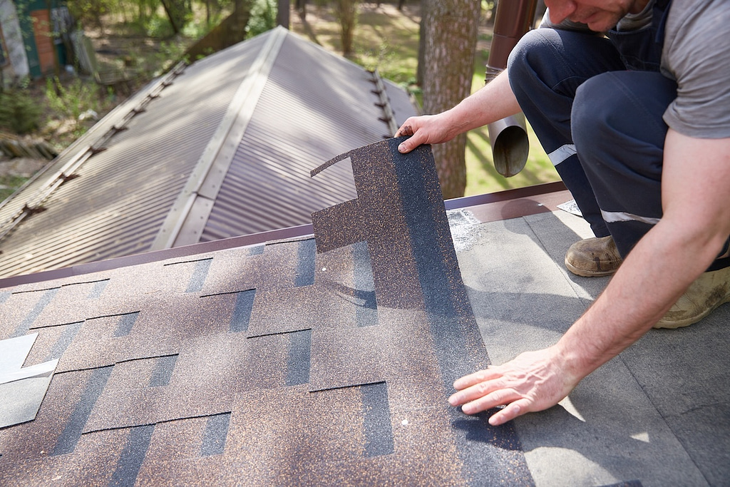 Roofer installing architectural shingles by laying them and aligning them on top of each other