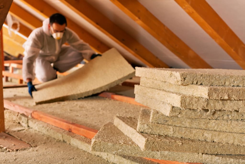 a man in a mask installing insulation on a roof