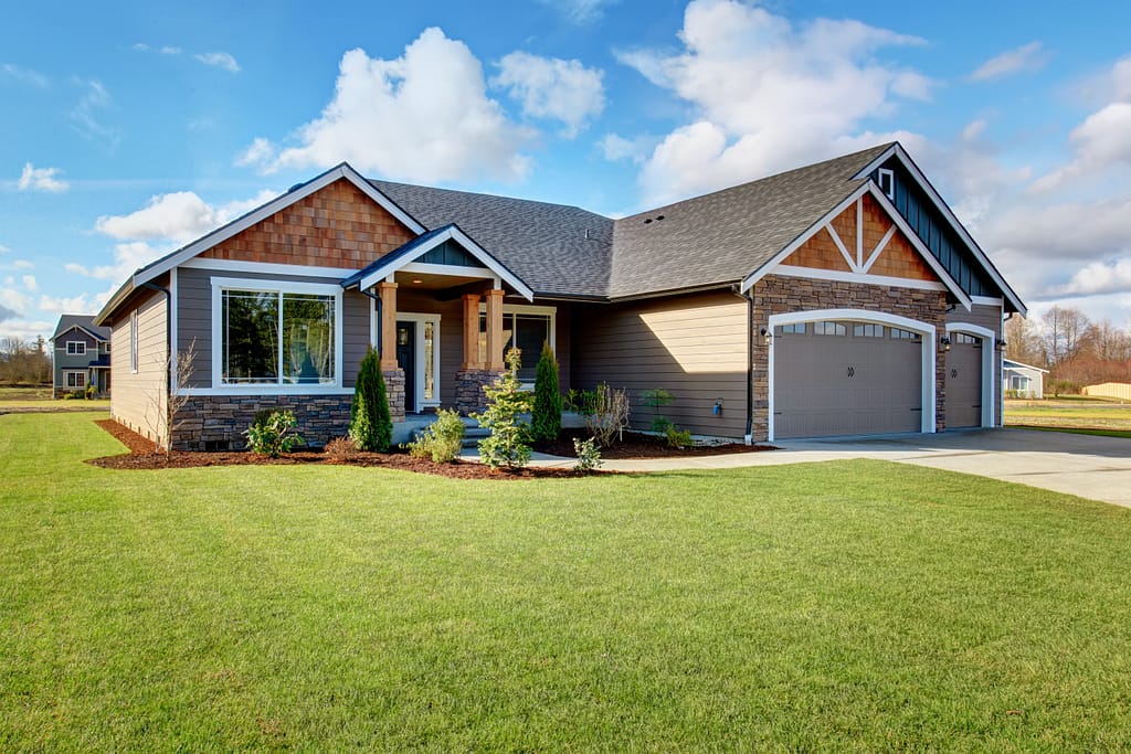 Large modern house with walkway and lots of grass.