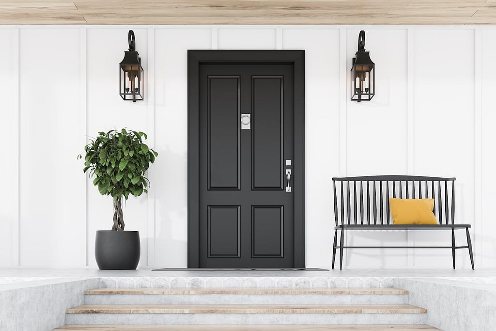 Black front door of white house, tree and bench