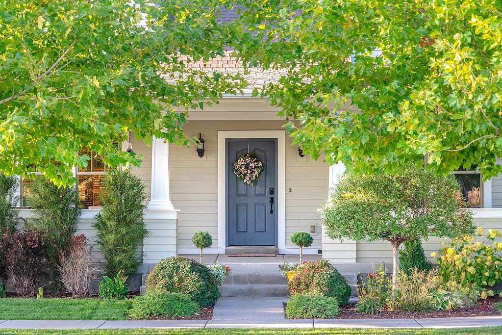 Front door of a home surrounded by leafy trees. Front door and porch of a home surrounded by leafy green trees in a city suburb in a street view