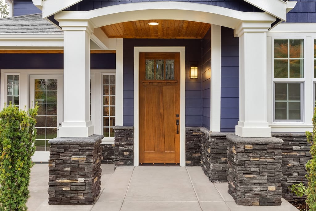 New Luxury Home Exterior Detail: New House Front Door and Covered Patio with Arch, Columns, and Elegant Design