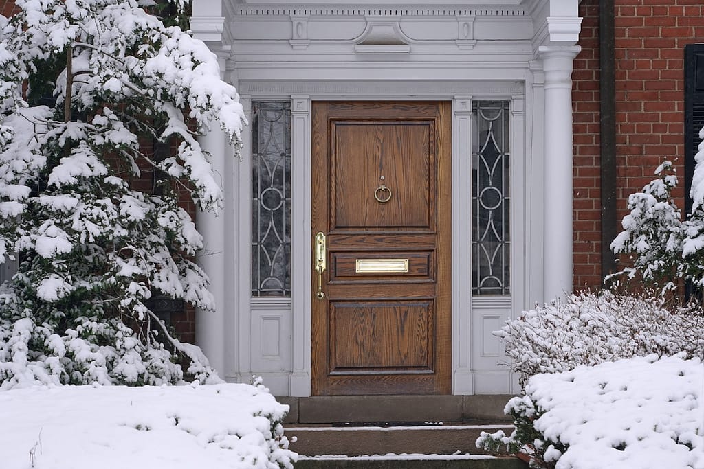 front door with elegant wood grain, with snow covered house entrance vintage doors