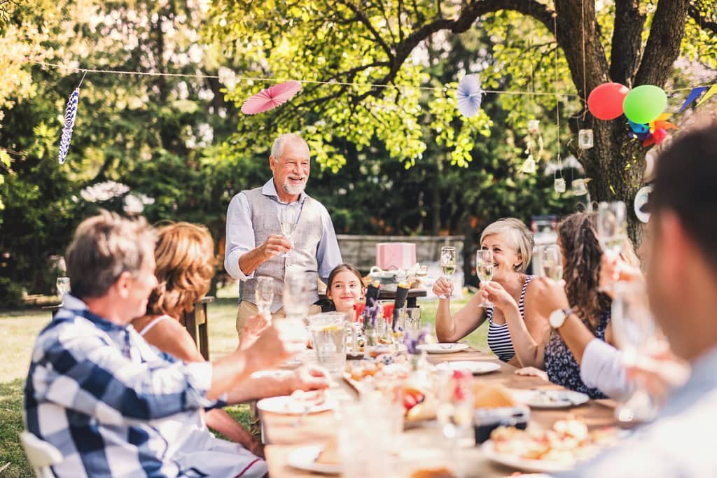 Multigenerational family outside of house with new roof having a garden party