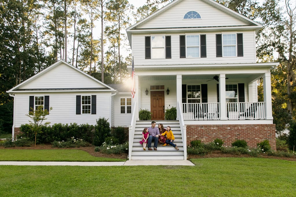 Family of Four With Daughters Sitting on the Steps Outside Their Home with new siding