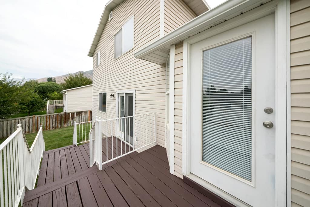 light colored vinyl siding on residential home with dark wooden deck