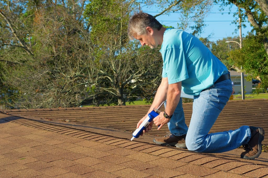 homeowner uses caulking to seal roof leaks as yearly maintenance for winter