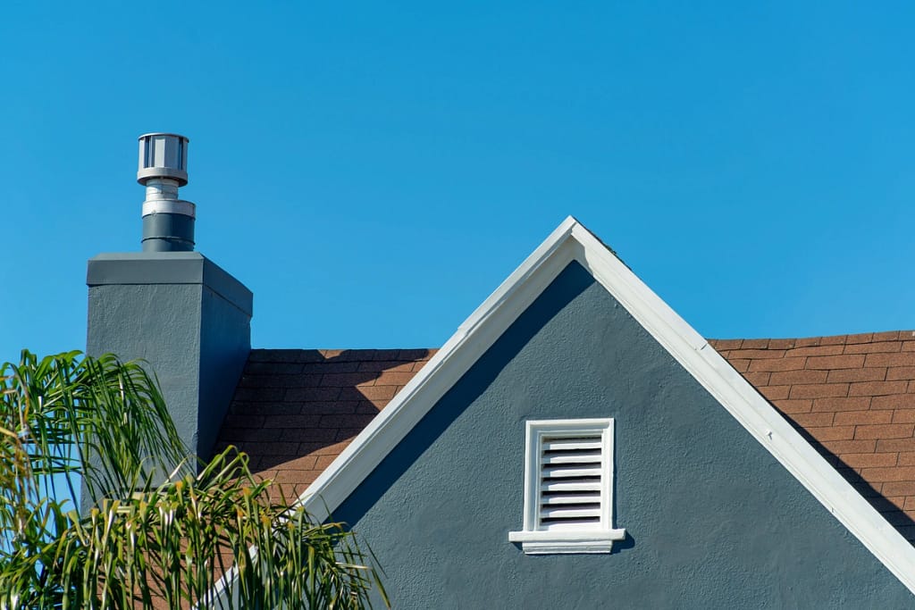 blue house with chimney and gable roof ventilation