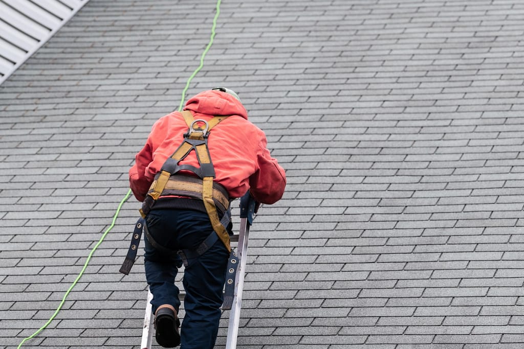 maintaining your roof through hired contractor using ladder to inspect rooftop