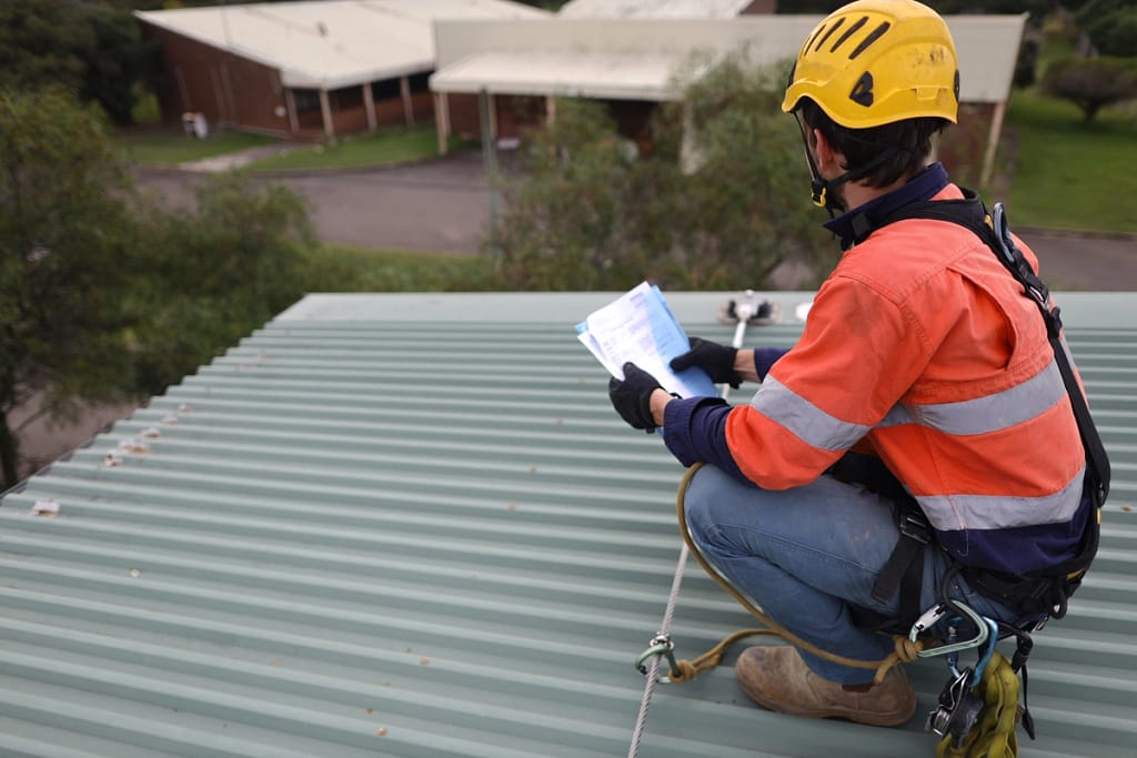 contractor inspects roof before performing maintenance before winter months
