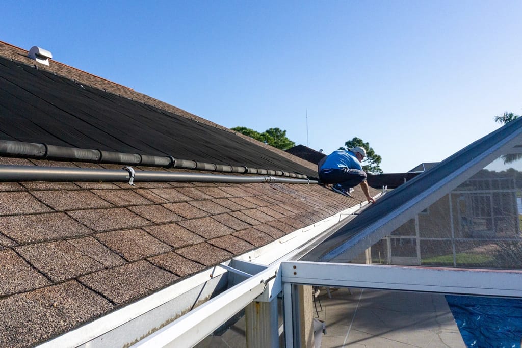 roofer on a shingle roof inspecting it