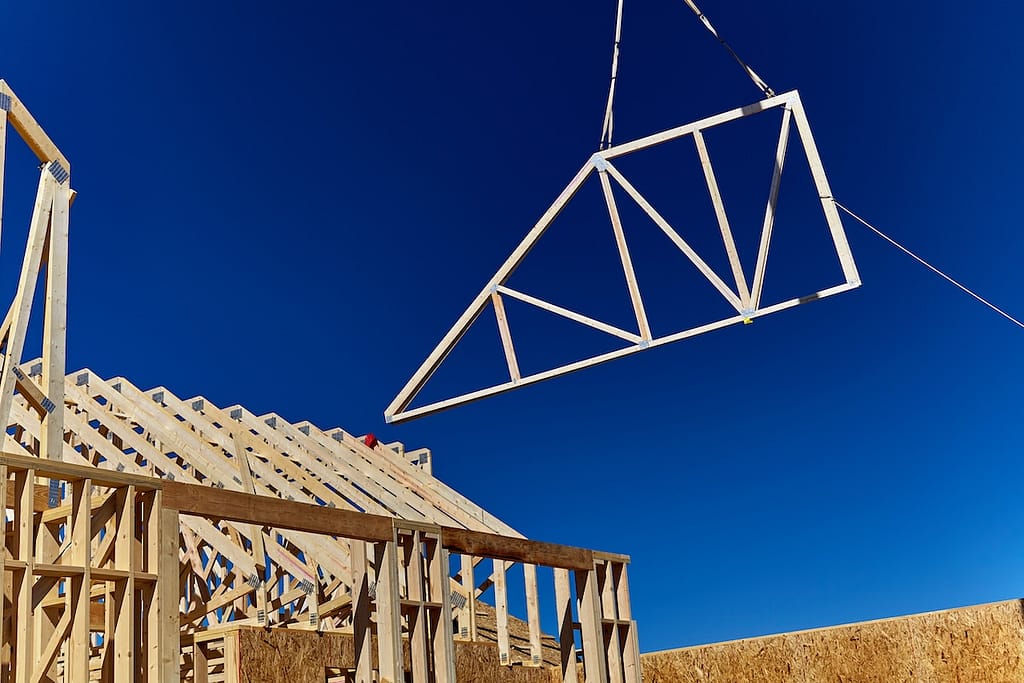 A wooden roof truss being lifted by a crane