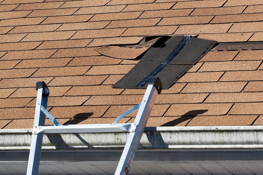 A ladder leads to the roof where shingle have been blown lose from wind and storm