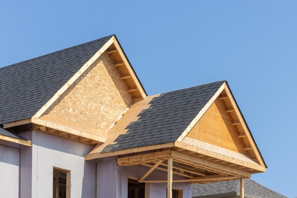 house with partially installed roof, revealing sheathing