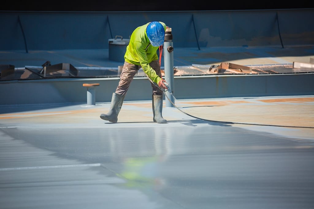 A male worker holding an industrial spray gun used for roof plate tank surface on steel industrial painting and coating.