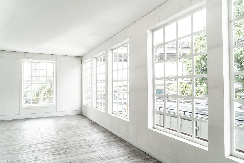 white and bright room with large white windows showing greenery