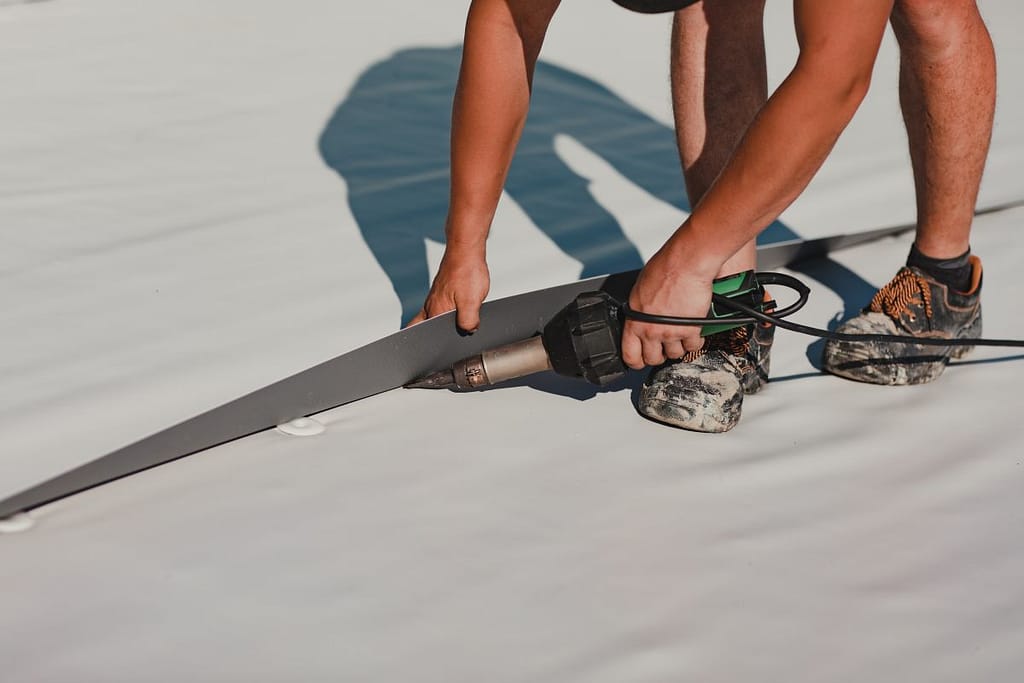 Worker welding pvc roof membrane by heater with welder machine