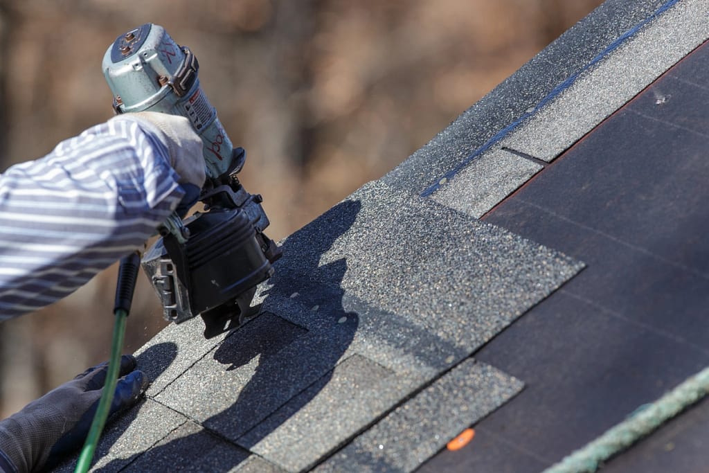 closeup of roofer performing roof leak repair using tools