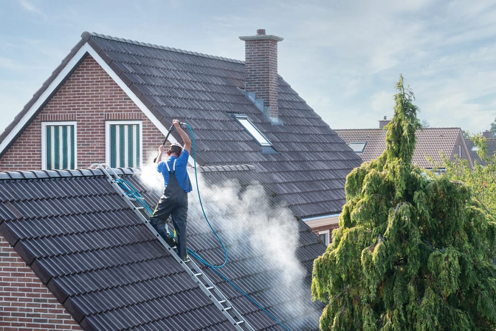 roofer power washes a roof