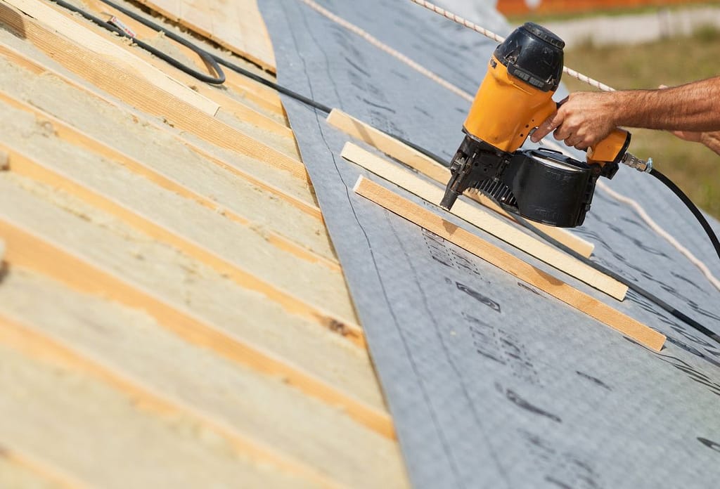 roofer with nail gun working on a roof