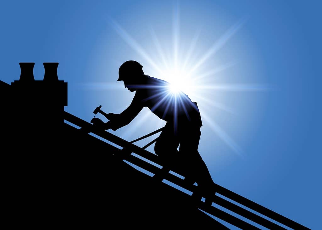 Silhouette of roofer working with blue sky background