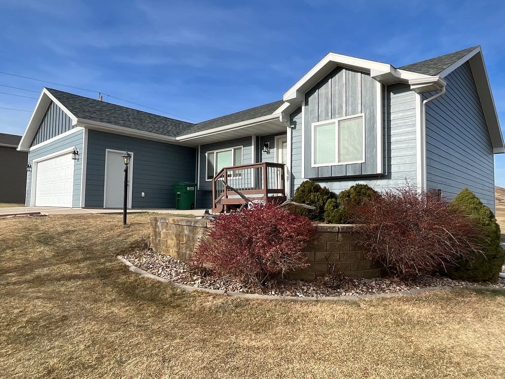 A single-story house with gray siding and a green shingled roof in rapid city sd after new siding installation