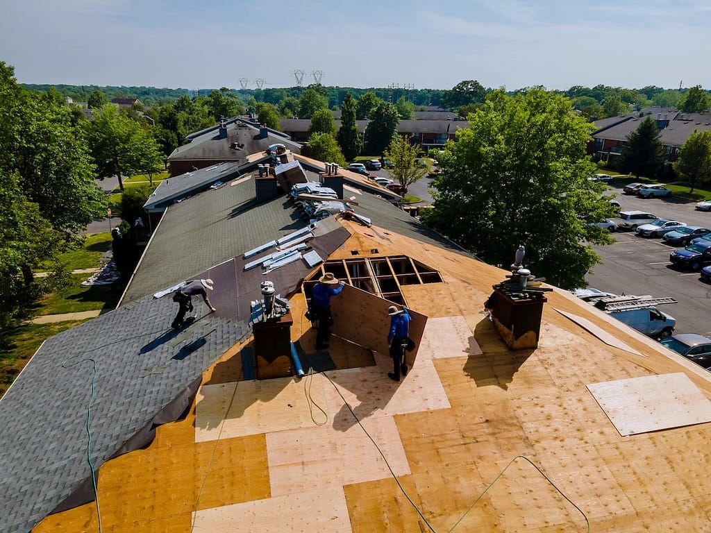 Construction workers installing new shingles on a large roof.