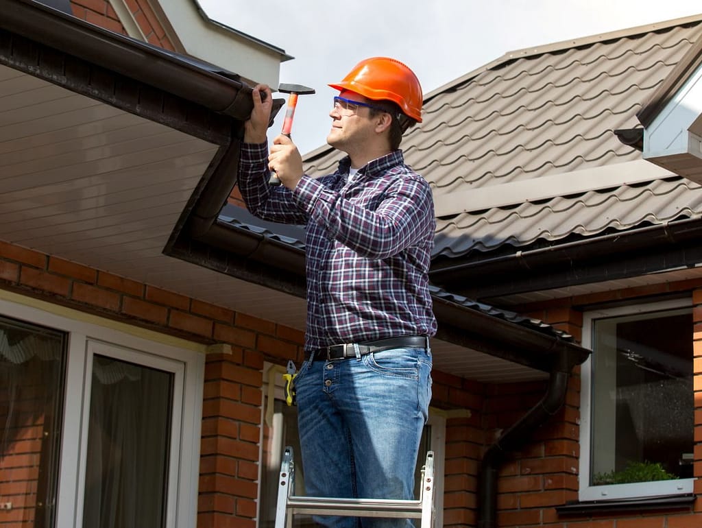 roof patch worker standing on a ladder