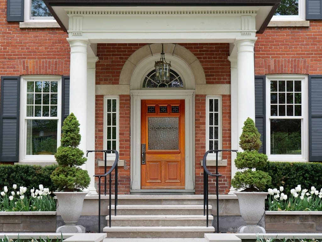 beautiful portico with white pillars in front of a home's brick exterior