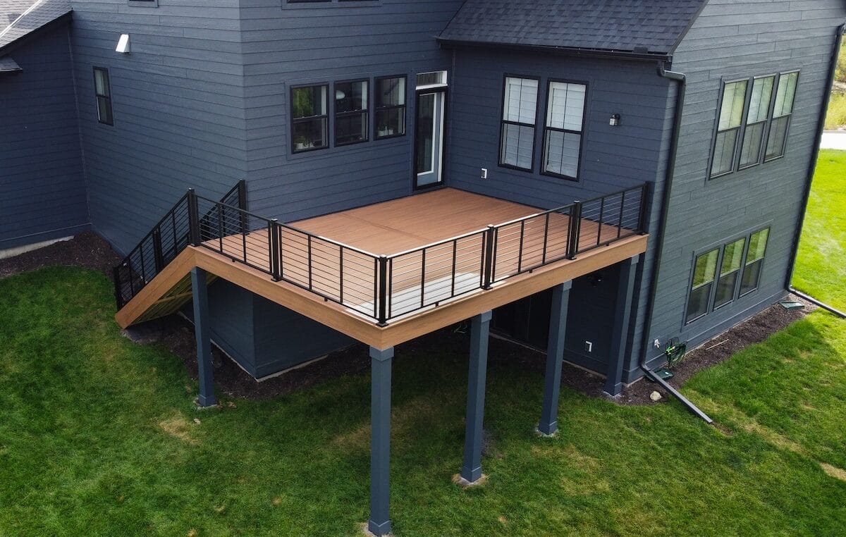 Aerial view of a house featuring a sleek, elevated wooden deck supported by columns in forest lake mn