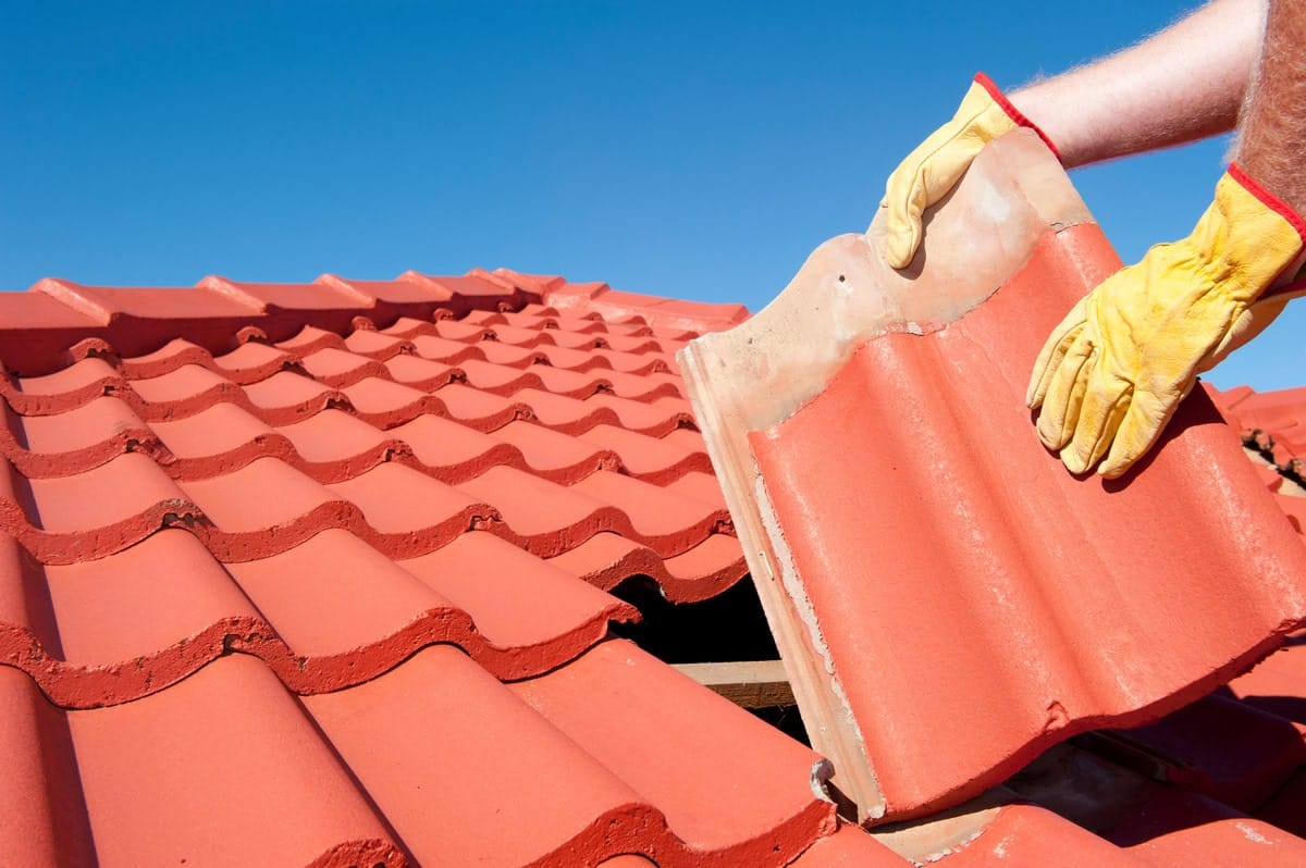 a worker is installing roof tiles