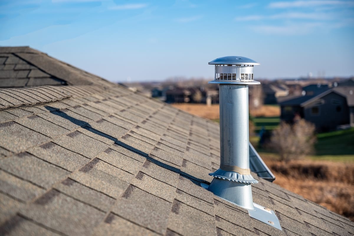 Typical rooftop chimney with a rain cap roof boot and shielding