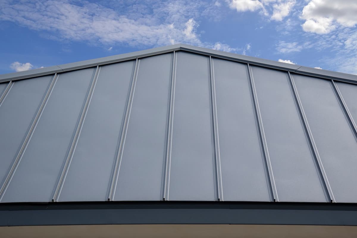 A close-up of a metal standing seam roof with vertical panels and raised seams