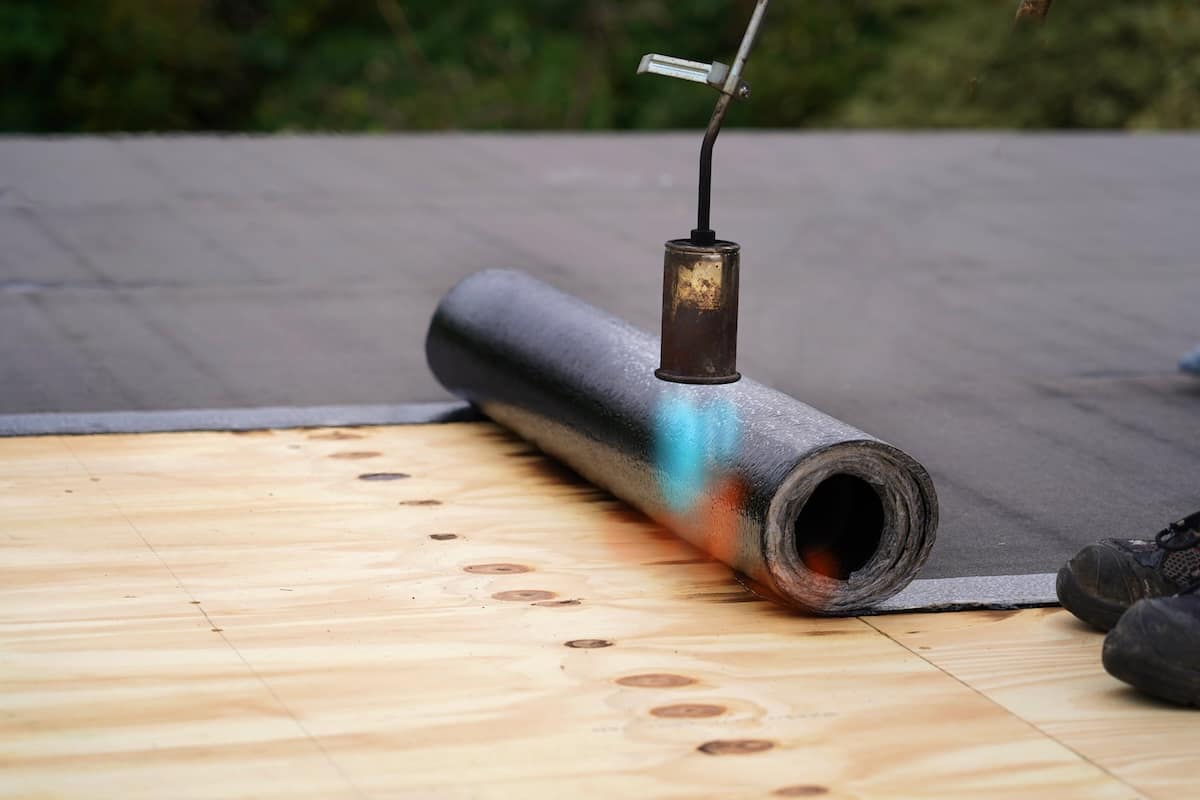 Bitumen roofing., with a gas burner and a roll of tar paper. Flat roof installation.