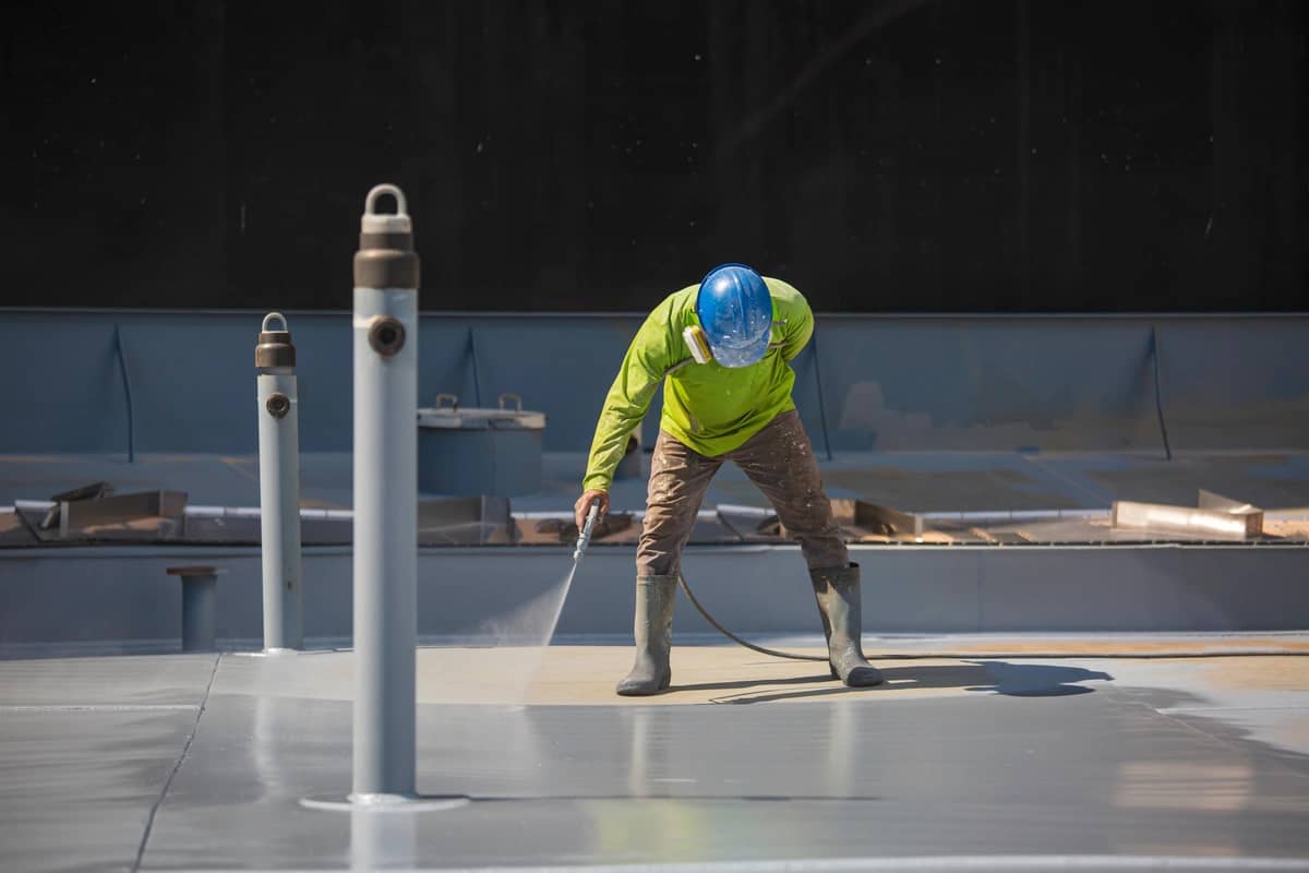 man on roof applying commercial roof coating