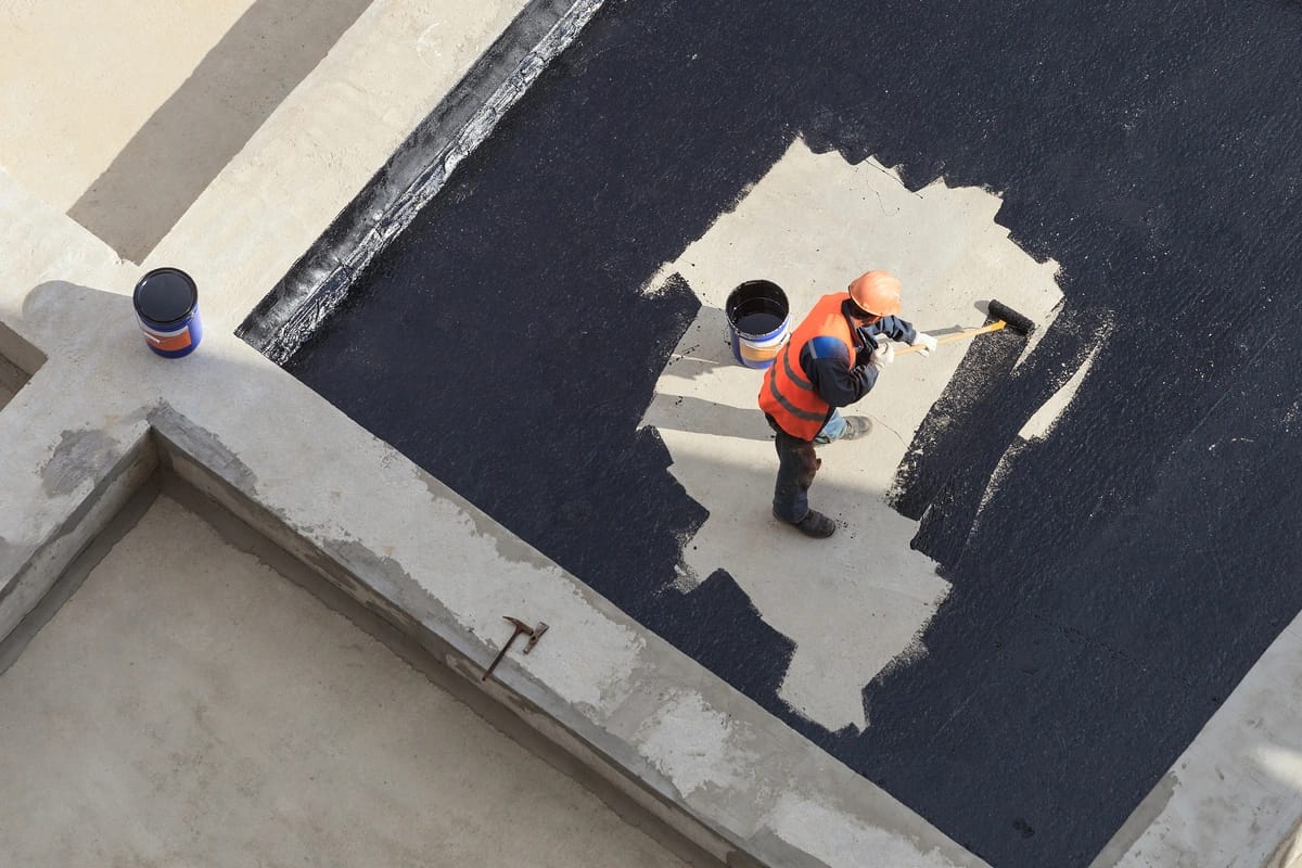 top view of worker applying the roof coating