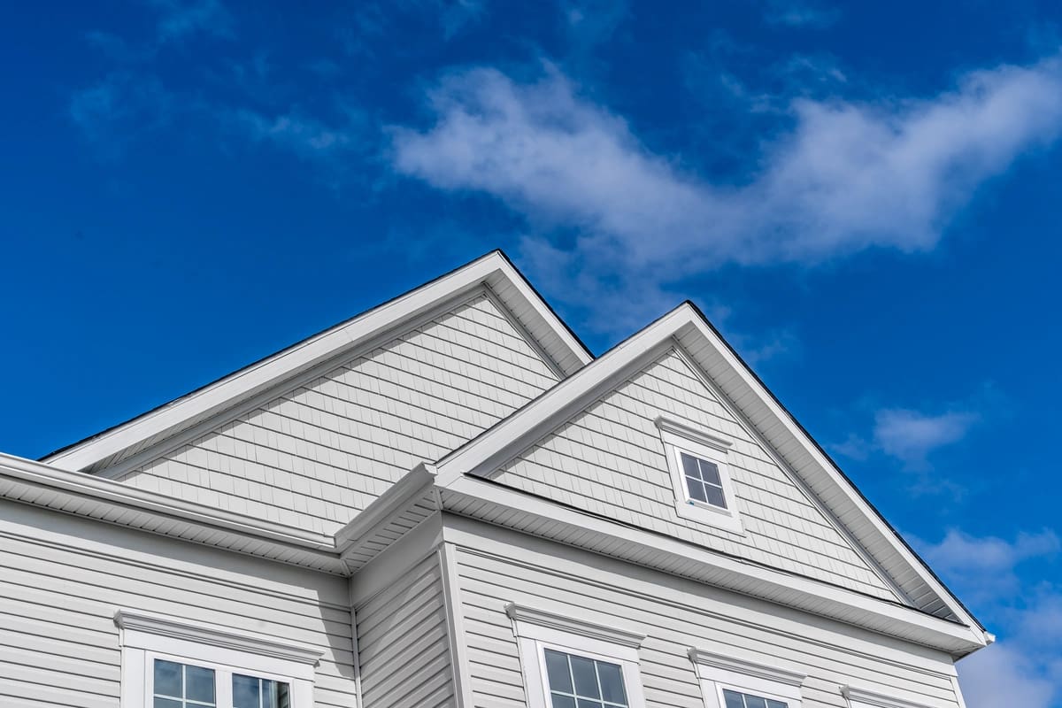 white siding on a house with blue sky and clouds in the background