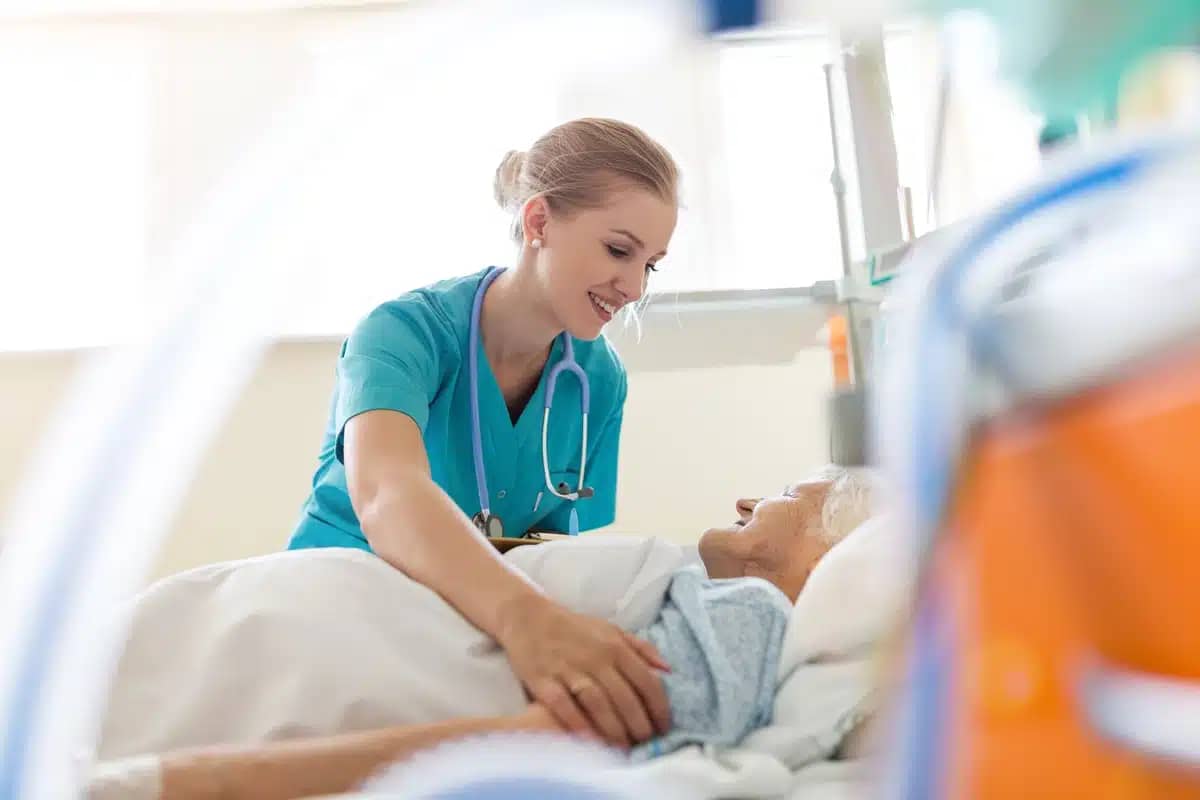 a nurse stands over an elderly woman lying in bed