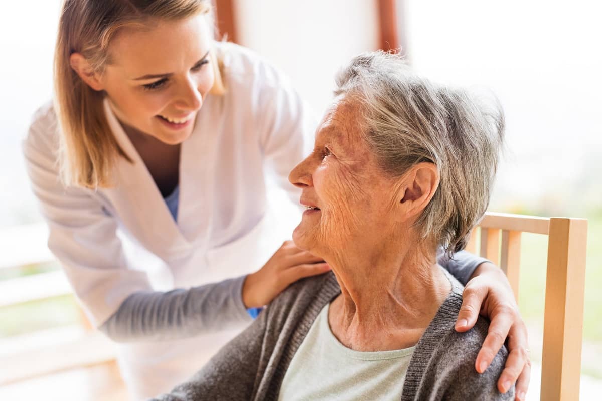 a nurse showing a gesture of care towards a old woman