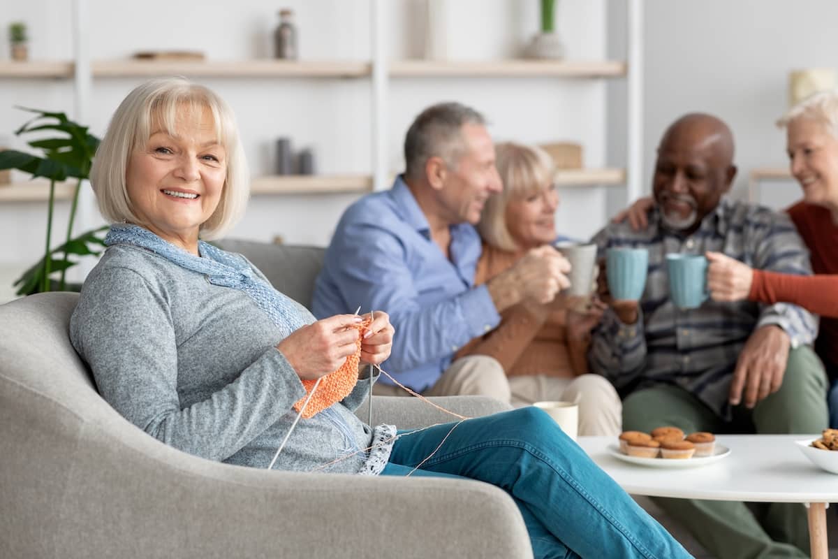 Elderly lady sitting at arm chair and knitting in living room