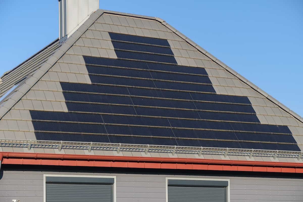 High-tech solar roof tiles on roof as solar power plant. Solar shingles installed on roof of residential home. Solar roof tiles integrated into roof.