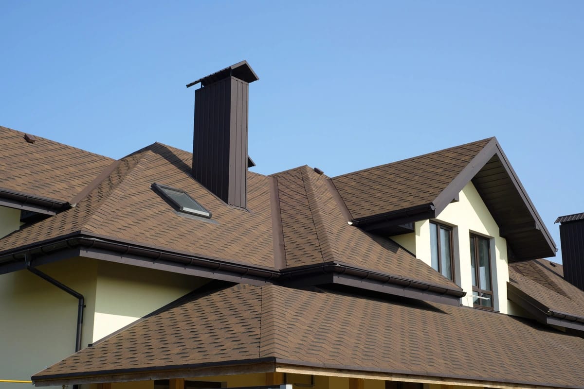 brown asphalt shingles installed on roof with skylight and chimney