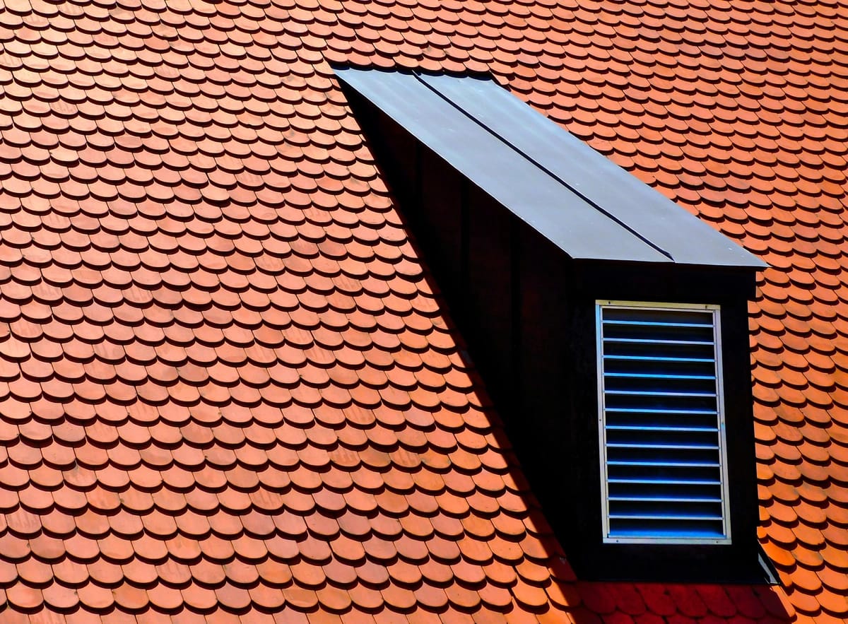 Close up of tile roof with square dormer and roof vent