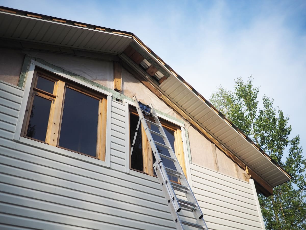 A ladder is propped against the side of a house under renovation.